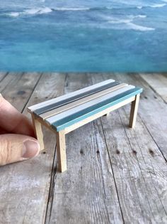 a miniature bench sitting on top of a wooden table next to the ocean and sky