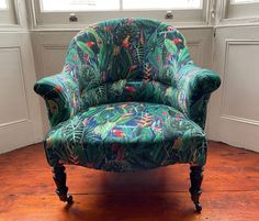 a green chair sitting in front of a window on top of a hard wood floor