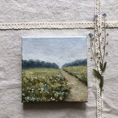 a painting on a piece of paper next to a small plant with flowers growing out of it