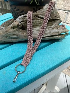 a crocheted leash on a bench with a potted plant in the background