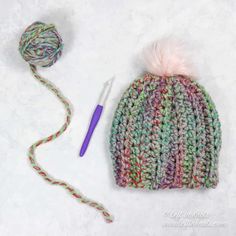 a crocheted hat with a ball of yarn next to it and a knitting needle