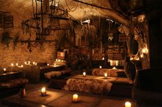 a dimly lit room with many candles on the floor and lights hanging from the ceiling