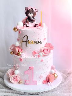 a pink and white cake with a teddy bear on top