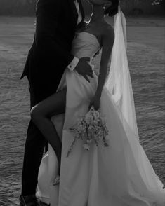 a bride and groom kissing in front of the ocean on their wedding day, black and white photo