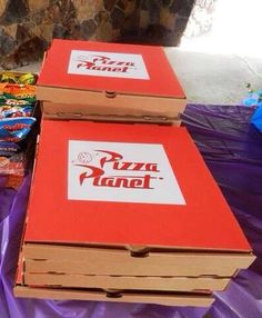 two pizza boxes stacked on top of each other next to bags of chips and candy