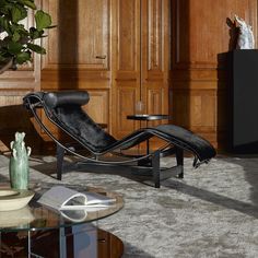 a black chaise lounge chair sitting on top of a rug next to a coffee table