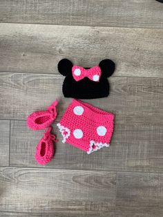 a crocheted minnie mouse hat, diaper cover and booties are laying on the floor