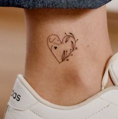 a small heart tattoo on the side of a woman's lower back ribcage