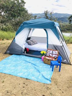 a blue and white tent sitting on top of a dirt field