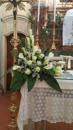 a table with flowers on it in front of a cross and alter at a church