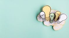 three lightbulbs are sitting on a plate with green leaves and blue background