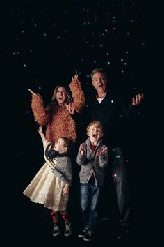 three children and an adult standing in front of confetti falling from the sky