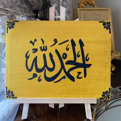 an arabic calligraphy is displayed on a easel in front of some other items