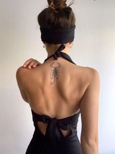 the back of a woman wearing a black swimsuit with a tattoo on her upper back