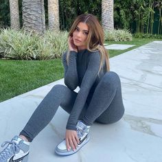 a woman is sitting on the ground with her legs crossed and wearing grey leggings