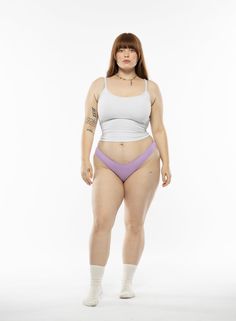 a woman in a white tank top and purple panties is posing for the camera with her hands on her hips