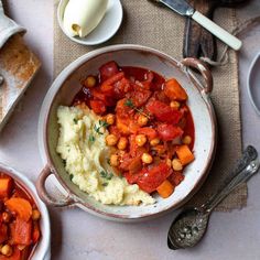 two bowls filled with mashed potatoes, carrots and chickpeas on a table