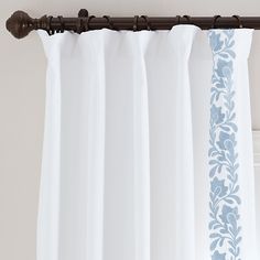 white curtains with blue floral designs hanging on a curtain rod