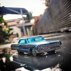 a toy car sitting on top of a table next to a building and water puddle