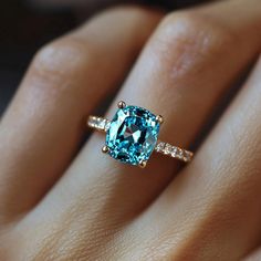 a woman's hand with a ring on it that has an aqua blue diamond in the center