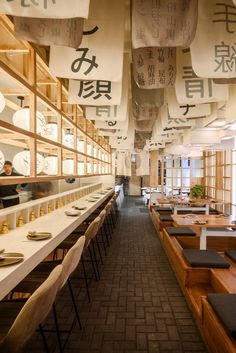 the interior of a japanese restaurant with tables and chairs lined up on either side of the room