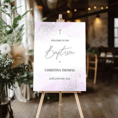 a welcome sign is on an easel in front of a table with flowers and greenery