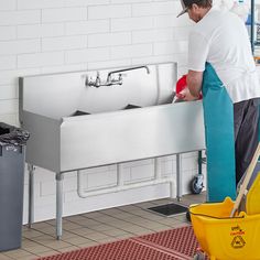 a man is washing his hands in the sink with a yellow mop and bucket