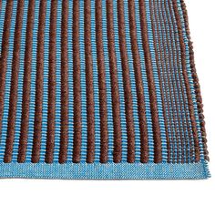 a blue and brown rug on top of a white surface with small holes in the middle