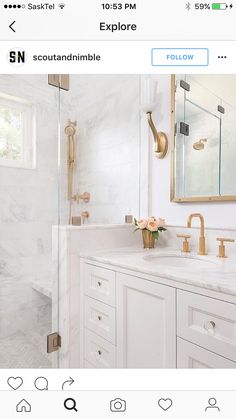 a white bathroom with marble counter tops and gold fixtures