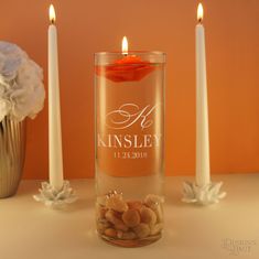 two candles are next to a vase with flowers in it and some rocks on the table