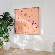 a painting hanging on the wall next to a potted plant in a white room