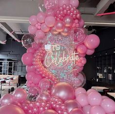 pink balloons are arranged in the shape of a cake with congratulations written on it and surrounded by other balloons