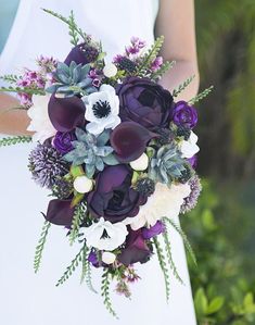 a bride holding a purple and white bouquet with succulents on her wedding day