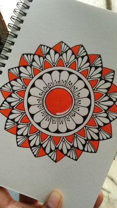 a hand holding a notebook with an orange and white flower design on the front cover