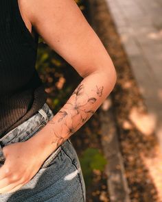 a woman with a flower tattoo on her arm is standing by the curb and looking down