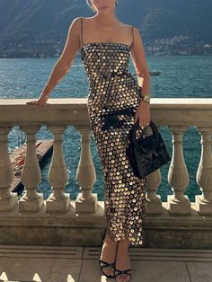 a woman standing on a balcony next to the ocean with her hand on her hip