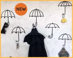 there are several umbrellas hanging on the wall with keys attached to it, and two coats hang from hooks