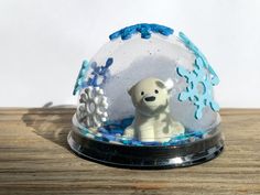 a snow globe with a white polar bear in it on top of a wooden table