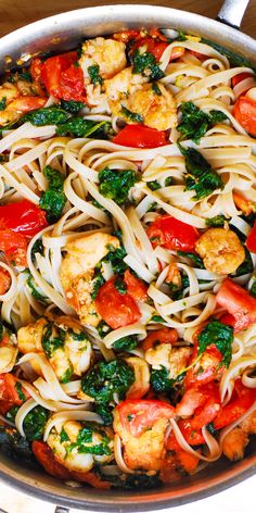 a pan filled with pasta and vegetables on top of a wooden table