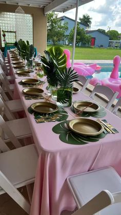 a long table set with plates and place settings for an outdoor party or gathering by the pool