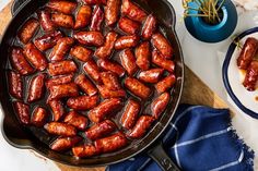 hot dogs are being cooked in a skillet on a table with other food items