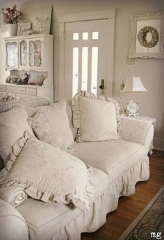 a living room with white couches and pillows on the back of it's sofa