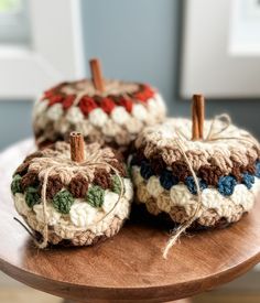 three crocheted pumpkins sitting on top of a wooden table