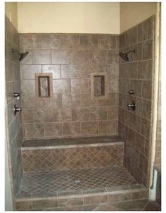 a walk in shower sitting next to a tiled wall and floor with brown tile on the walls