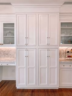 a kitchen with white cabinets and marble counter tops in the center, along with wooden floors