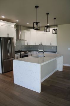 an empty kitchen with white cabinets and stainless steel appliances in the center island, surrounded by wood flooring