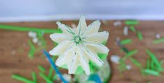 a close up of a flower in a vase on a table with green and blue streamers