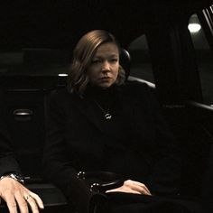 a woman sitting in the back seat of a car next to a man wearing a suit