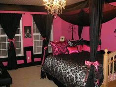 a bedroom with pink walls and black bedding, chandelier hanging from the ceiling