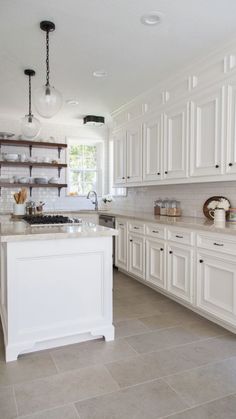 a large kitchen with white cabinets and marble counter tops, along with open shelving